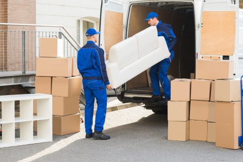 Movers relocating desks and IT equipment during an office move