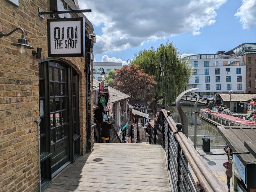 A covered loading area at Bermondsey Wharf with a high, dark metal roof supported by green and black structural beams, providing shelter for the furniture transport and packing process during home rel